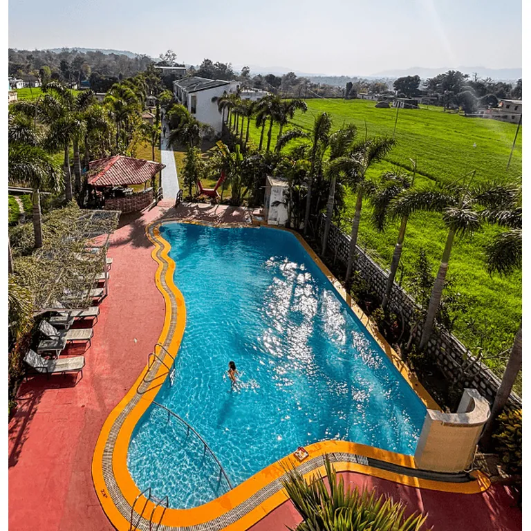 Outdoor swimming pool and landscaped resort grounds at The Neeraj River Forest Resort