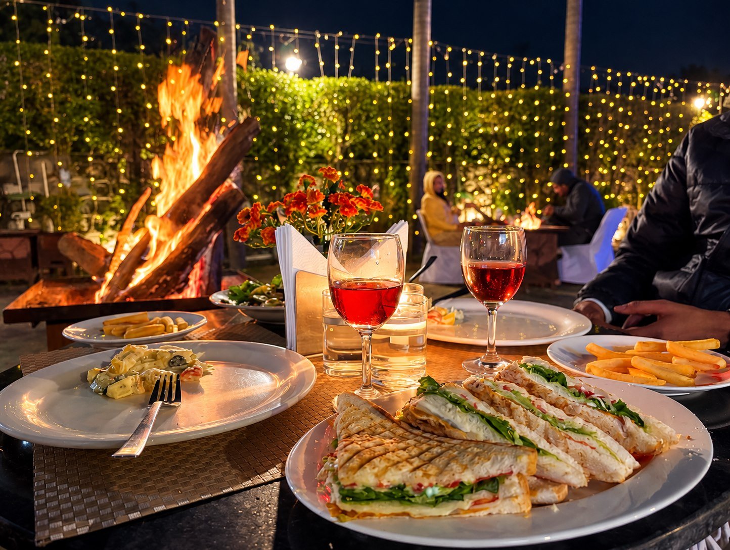 Evening dining with food and drinks beside the resort bonfire and string lights